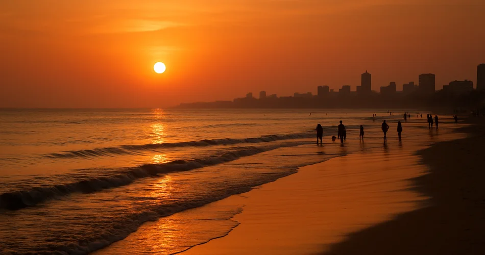 Sunset glows over the sea as distant silhouettes stroll along Juhu Beach.